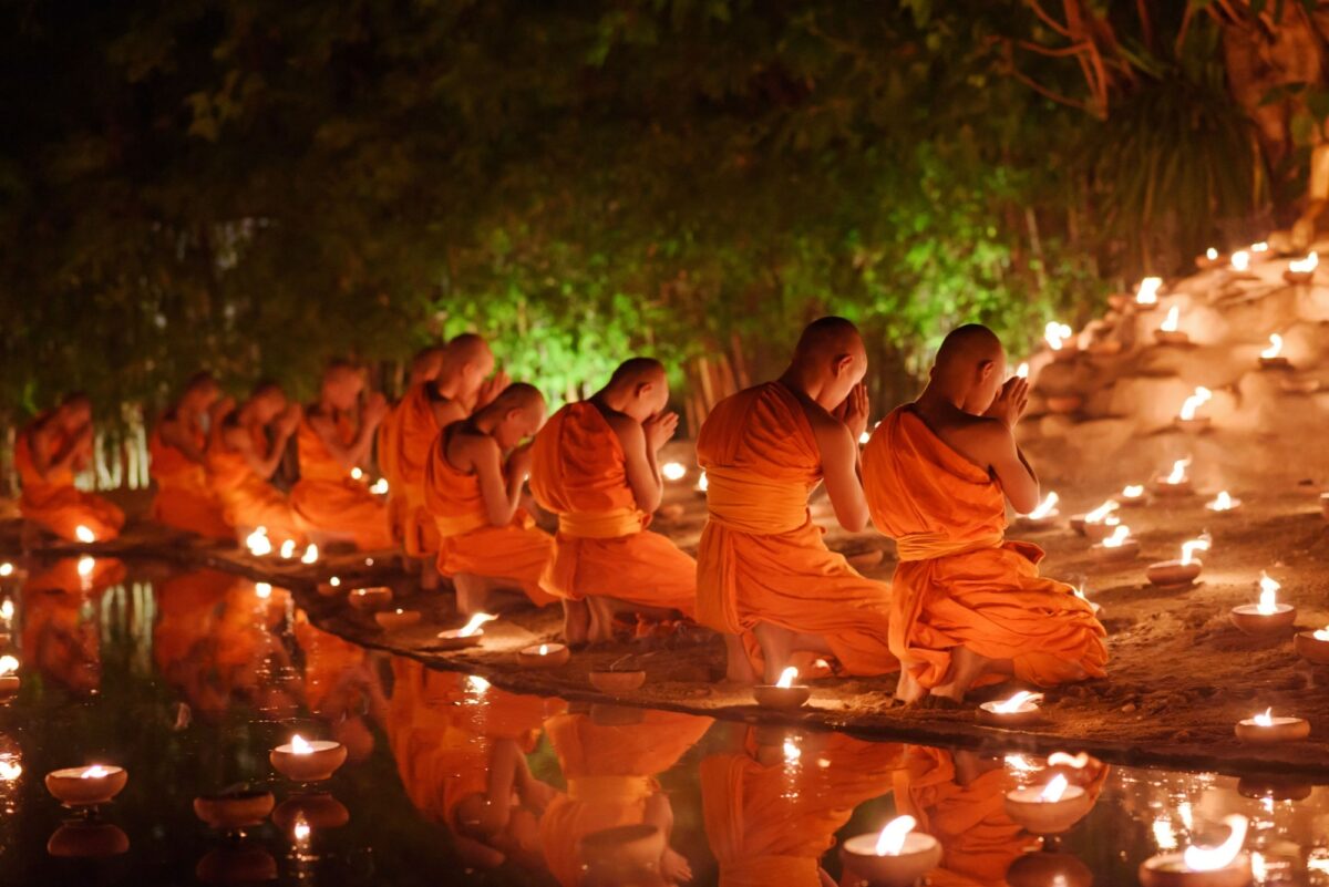 Thailand Chiang Mai monks sitting meditate with many candle in Thai temple at night