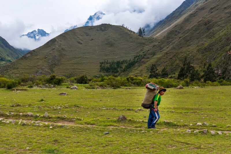 Porter carrying heavy pack on the inca trail peru